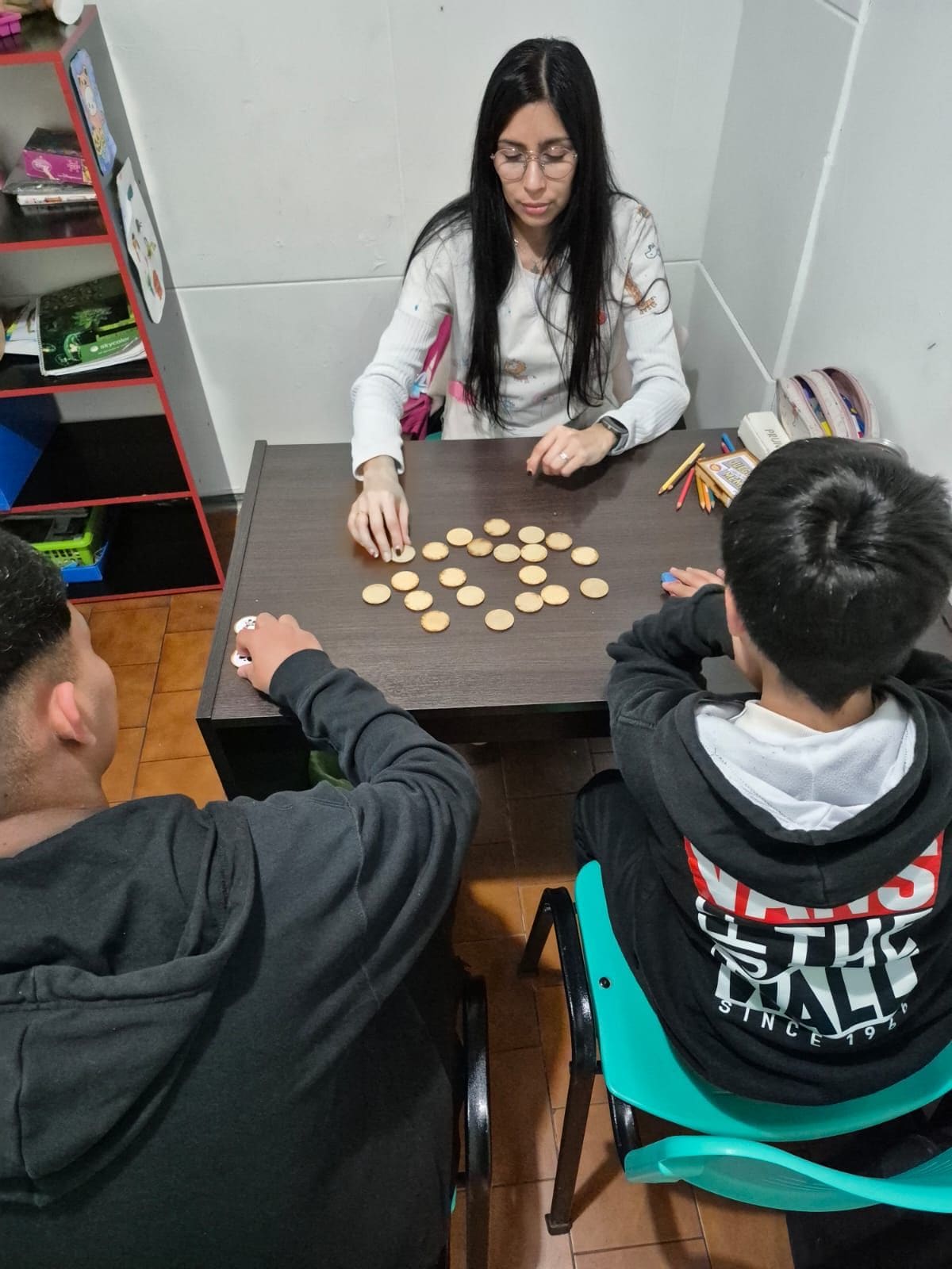 Psicopedagoga de AZAI con dos pacientes y un juego de fichas sobre la mesa